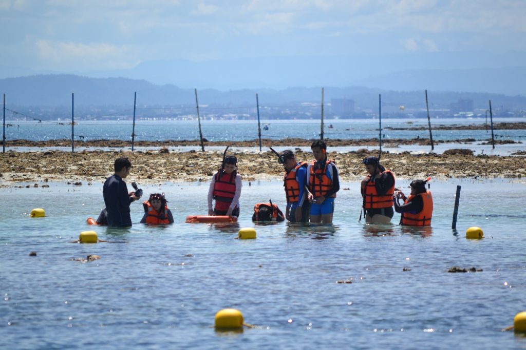 Visitors learning about giant clam habitats in shallow coastal waters of the Philippines