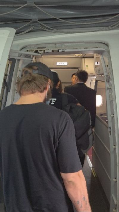 Vitaly Zdorovetskiy walking through an aircraft boarding tunnel while being escorted by authorities during deportation