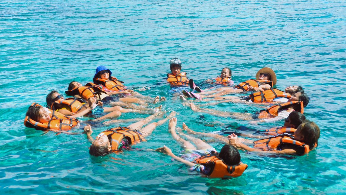 Family members swimming together in clear blue waters during their Mati City vacation.