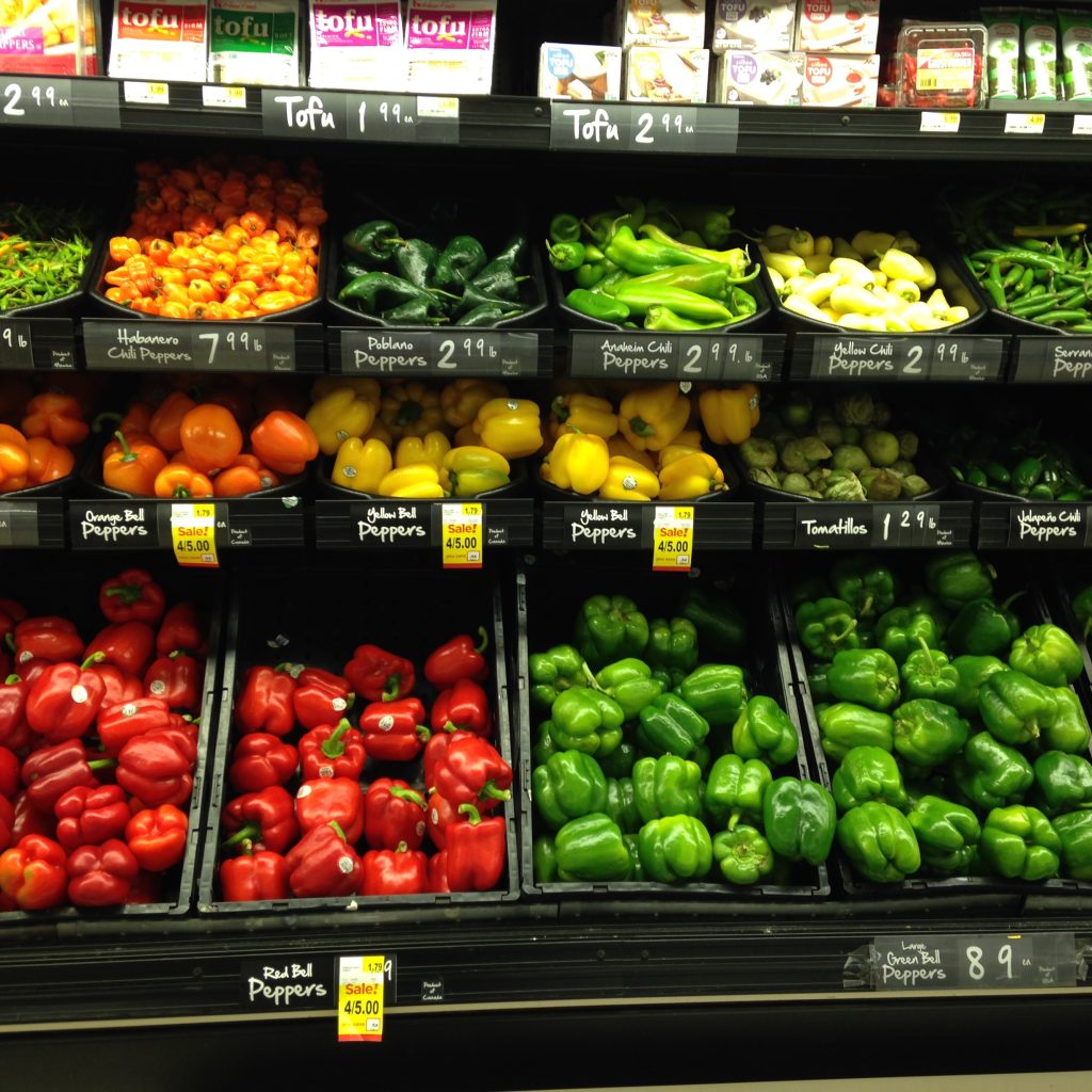 Different varieties of bell peppers arranged in a grocery display section