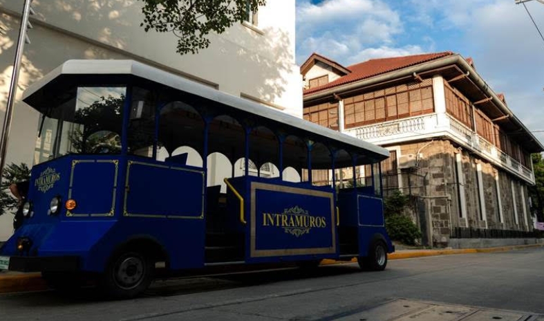 Blue e-tranvia electric vehicle driving along Intramuros streets showcasing sustainable transport in Manila