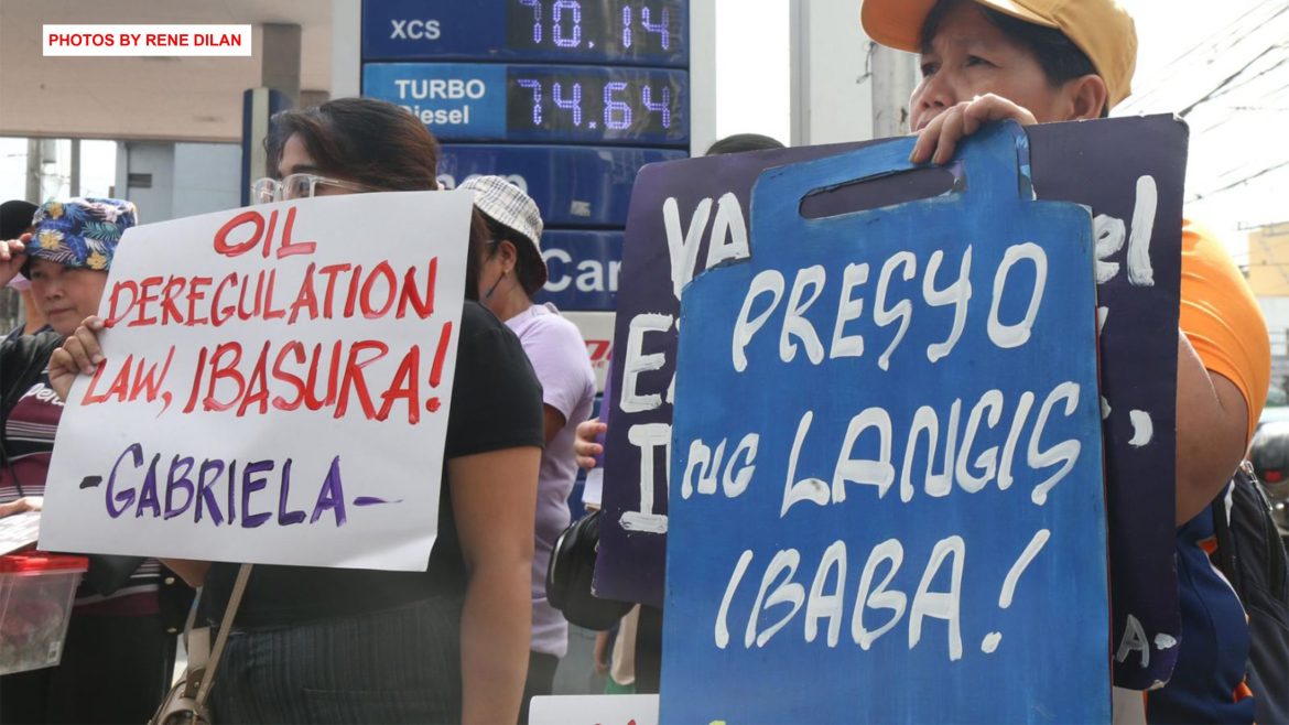 Fuel price protest Philippines as commuters hold placards calling for lower oil prices and higher wages during a rally near a gasoline station