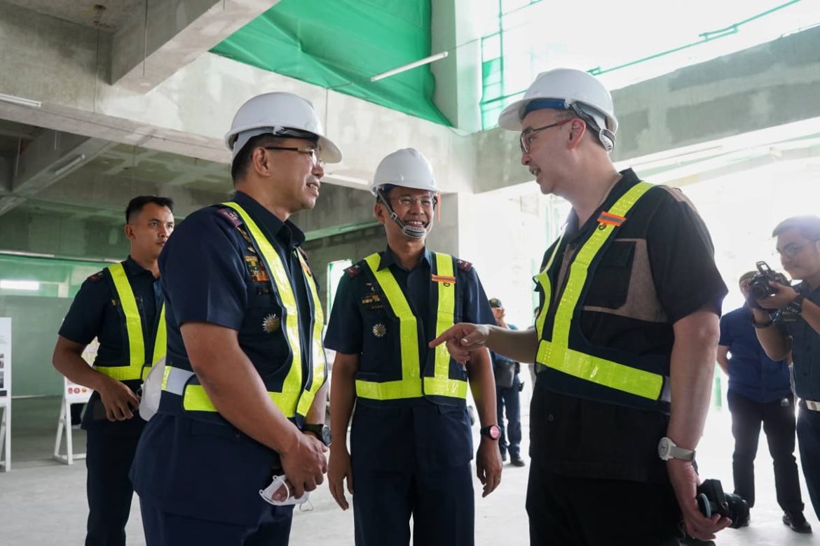 Government officials wearing safety gear discuss the progress of the forensic laboratory project during an inspection.